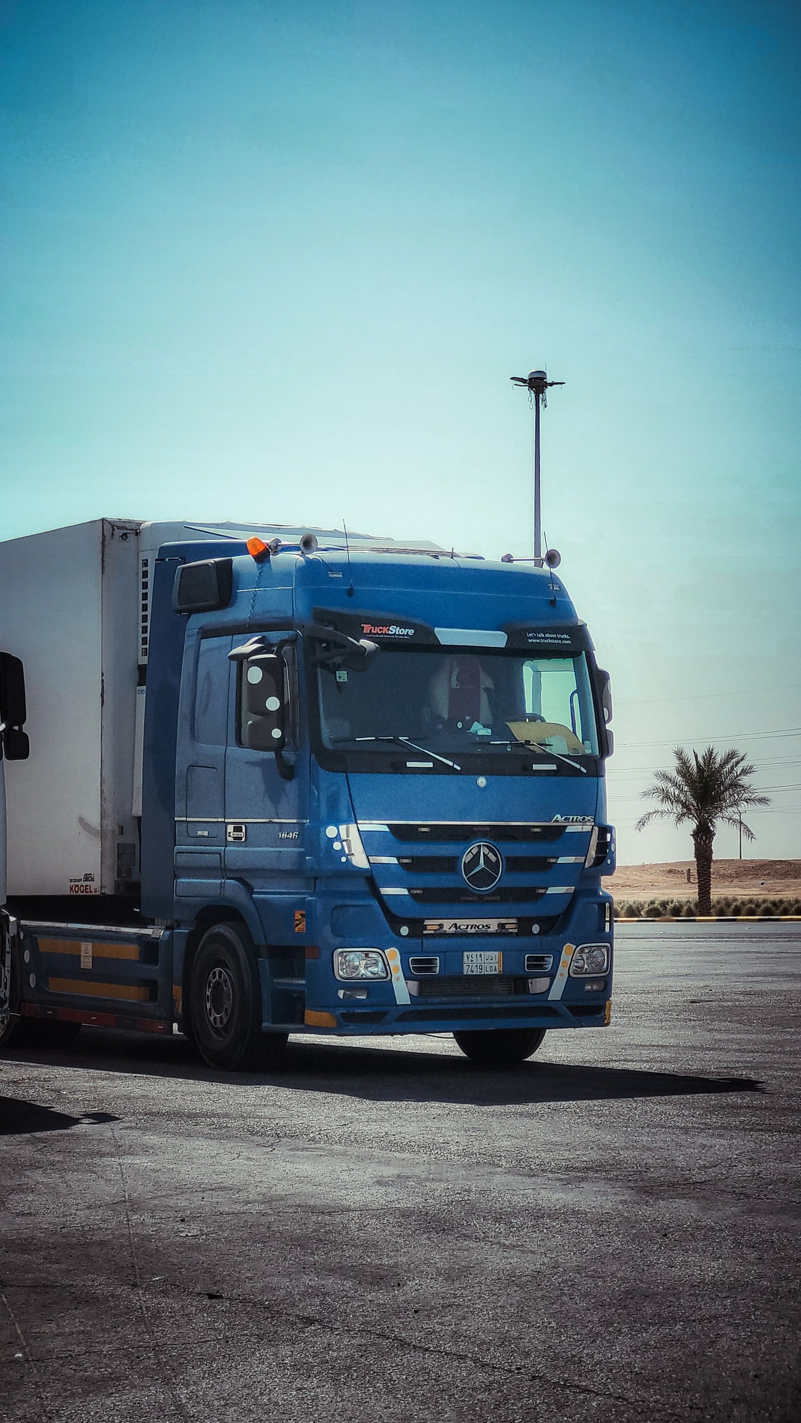 Blue tractor with a reefer trailer staged in a lot